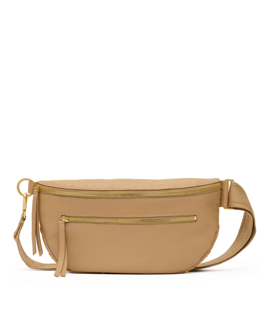 A tan leather waist bag with gold-tone hardware, featuring a top zipper, a front zip pocket, a tassel charm, and an adjustable shoulder strap, shown against a plain white background.