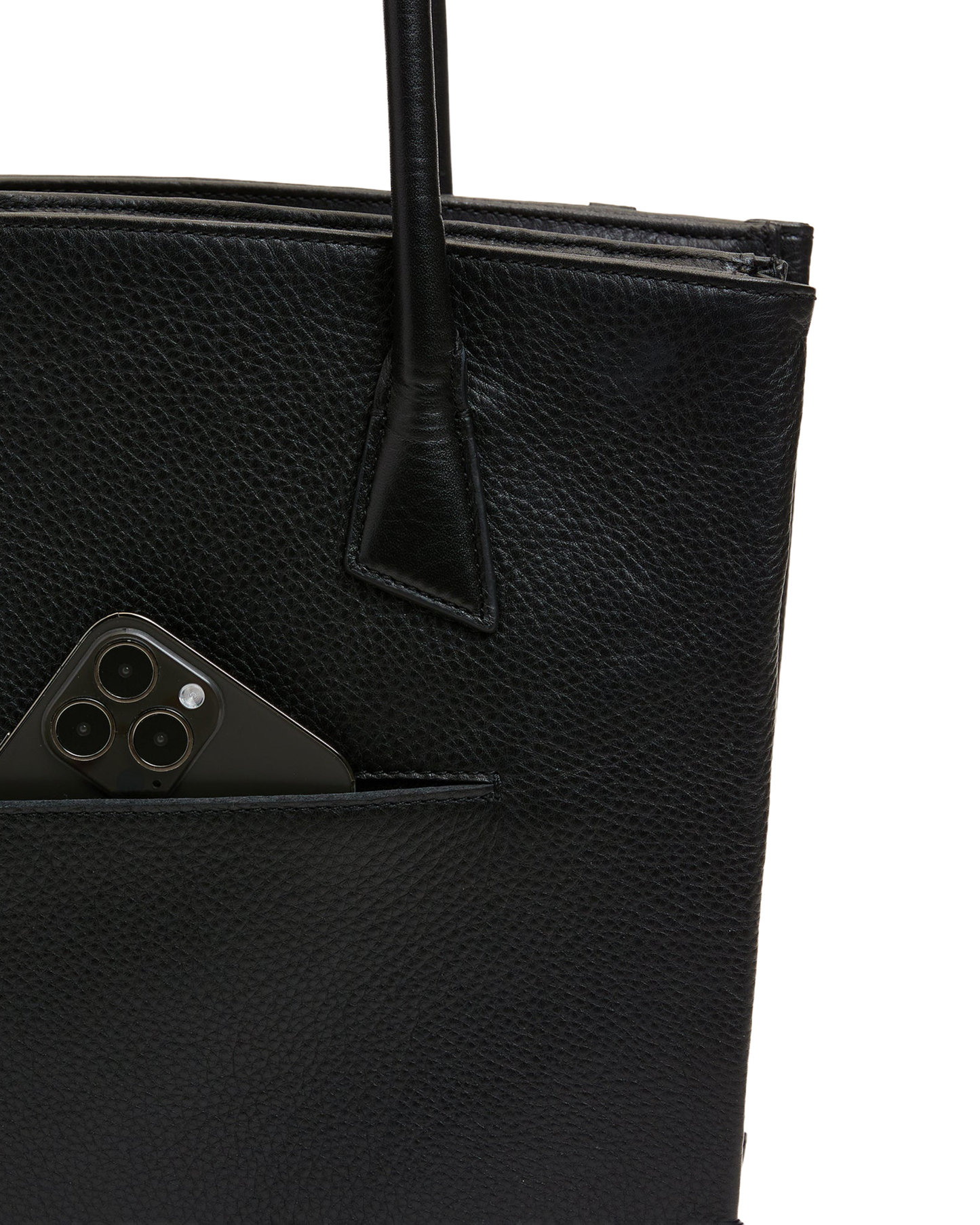 Close-up of a black pebbled leather tote bag with a side pocket holding a dark smartphone, shown against a plain white background.