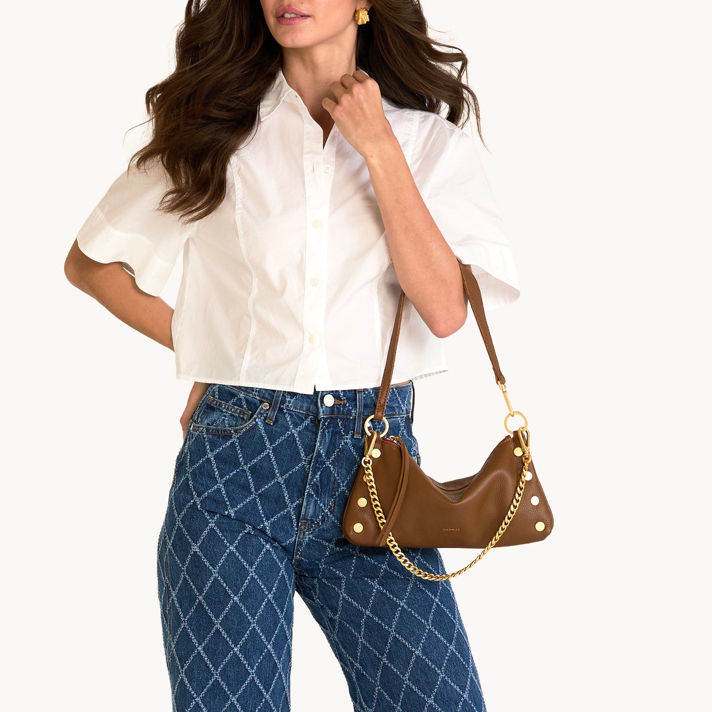 Woman holding a brown handbag against a white background