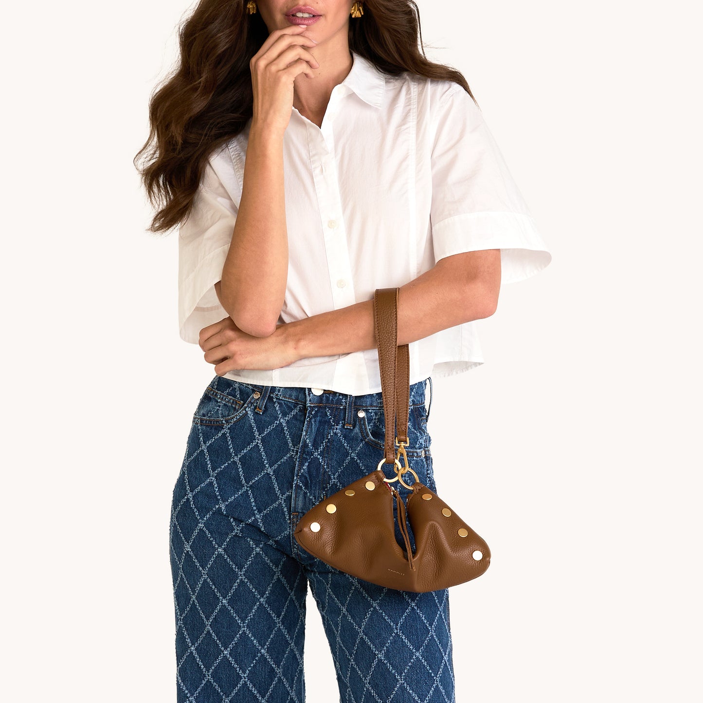 Woman holding a brown handbag against a white background