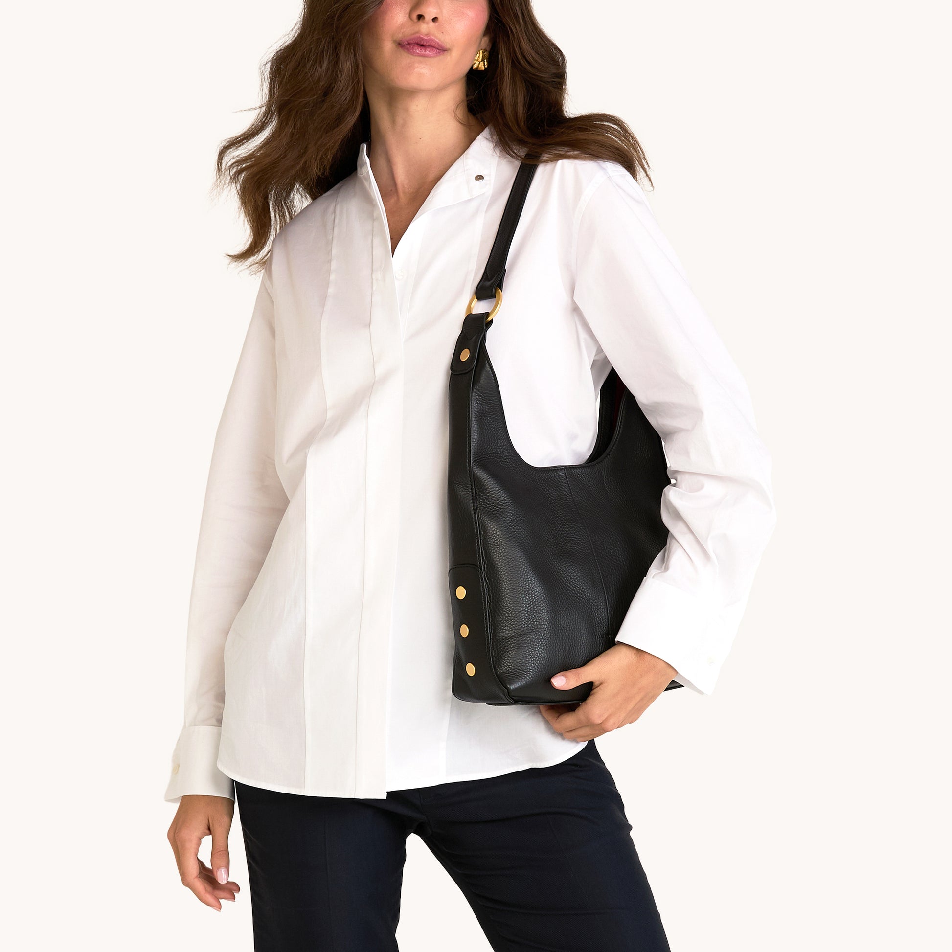 Woman holding a black leather bag against a white background