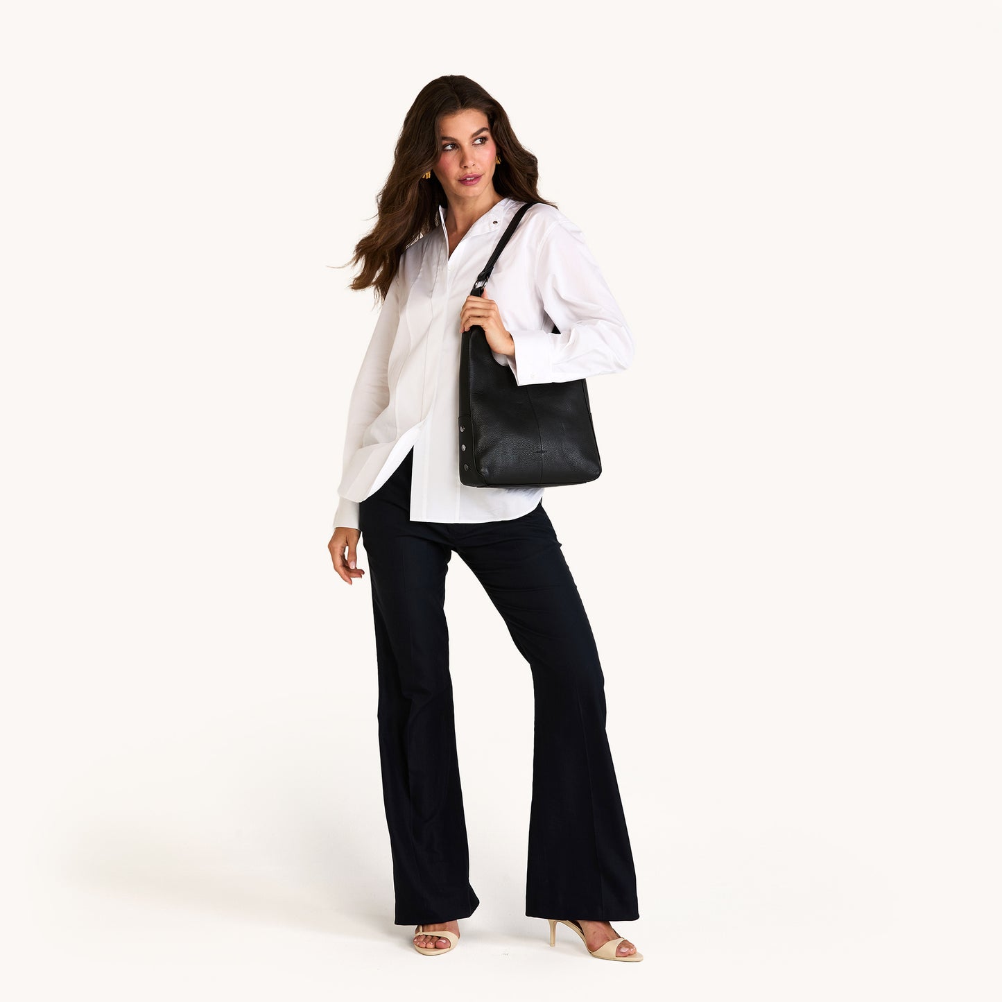 Woman holding a black handbag against a white background