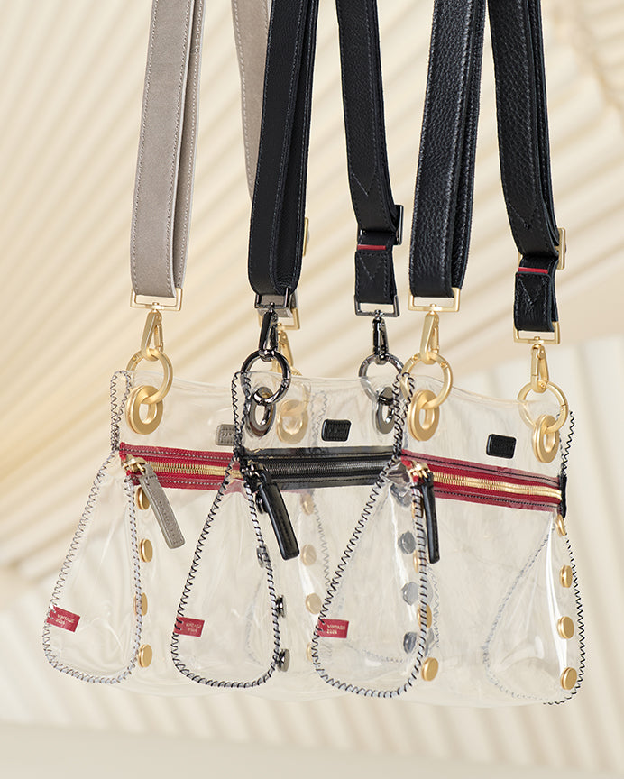 Image of three Tony Sml clear bags. Styles shown clear pewter brushed gold red zip, clear black gunmetal, clear black brushed gold red zip.