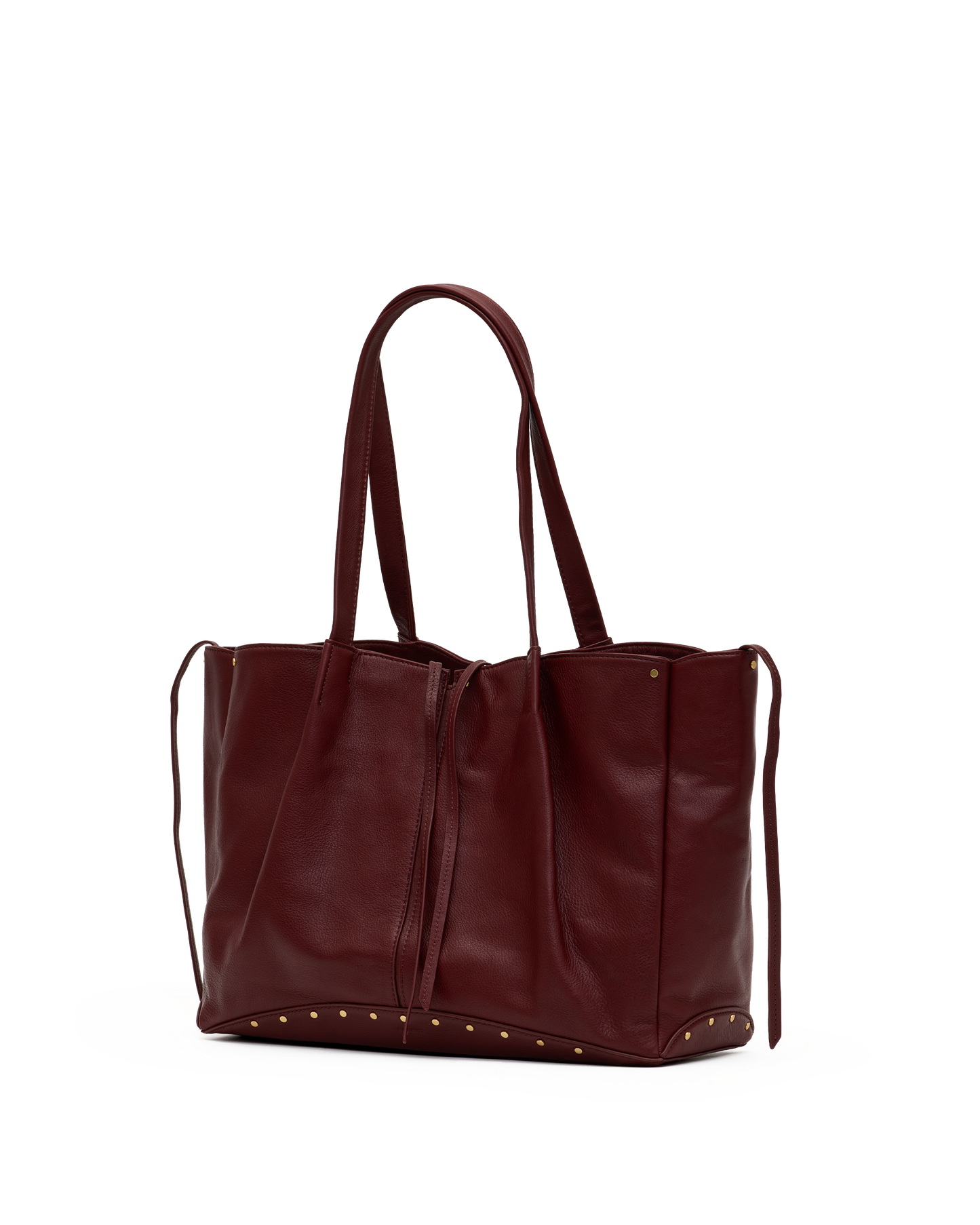 A dark burgundy leather tote bag with double shoulder straps, drawstring ties, and gold-tone metal studs along the bottom edge, shown against a plain white background.
