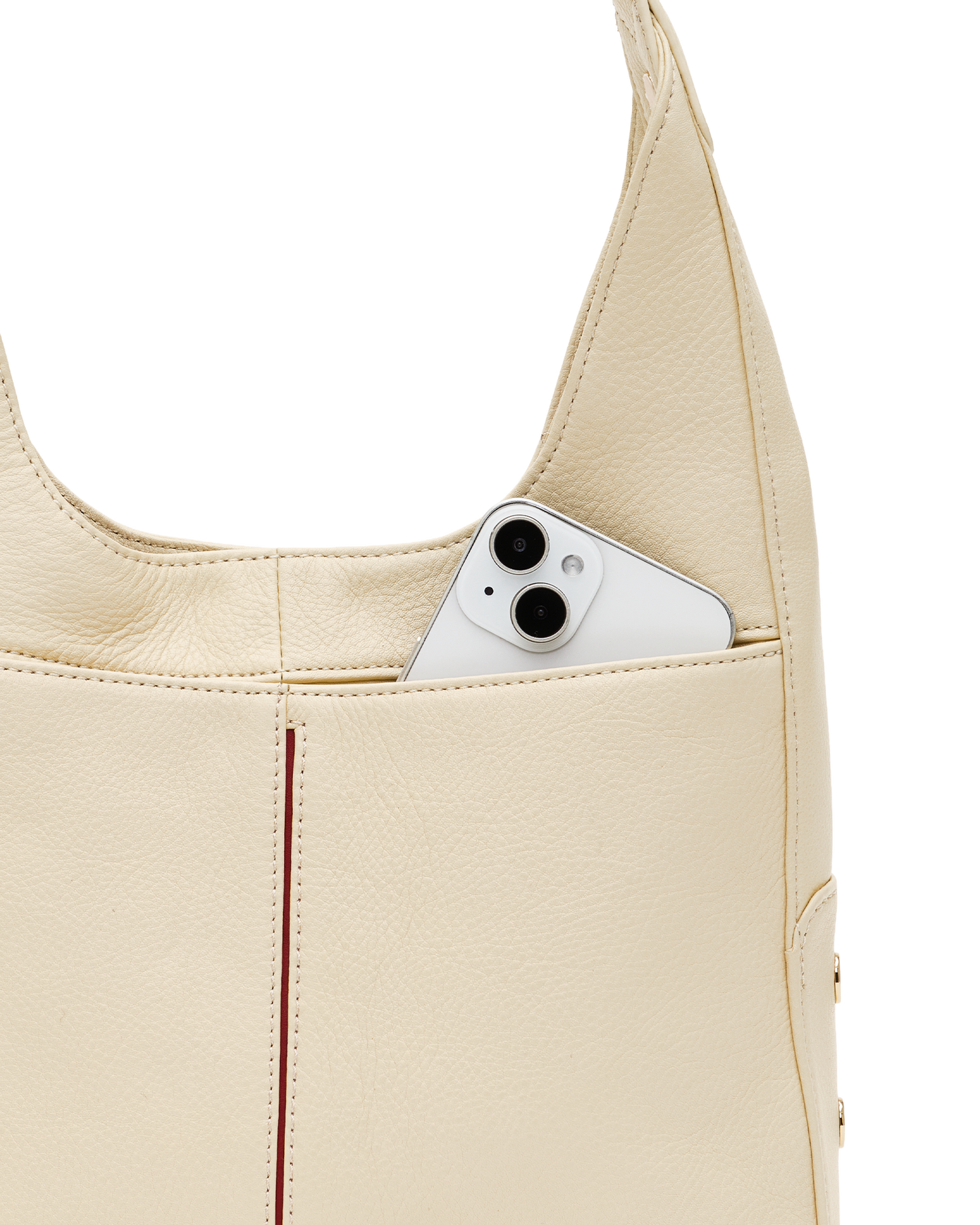 Close-up of a cream-colored pebbled leather shoulder bag with a silver smartphone tucked into its side pocket, set against a solid white background.
