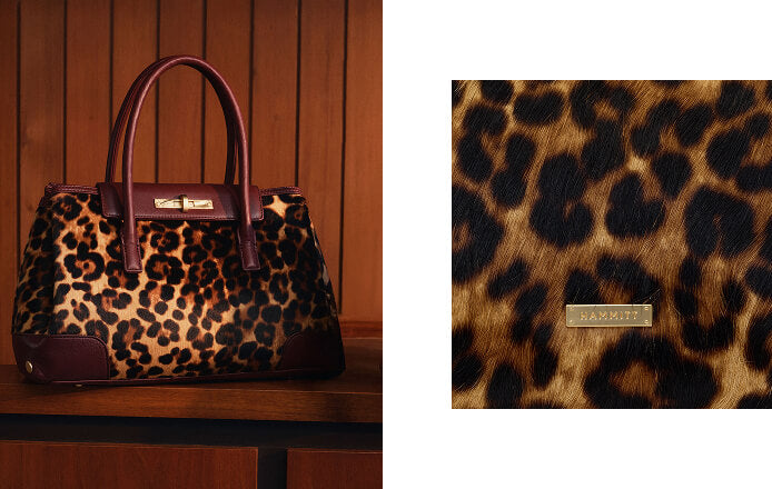 A leopard-print handbag with dark brown leather trim and handles, shown on a wooden surface against a wood-paneled background, with a close-up inset of the leopard pattern and a gold-tone HAMMER logo plaque.
