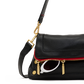 A close-up of a black pebbled leather shoulder bag with a red piping accent along the front zipper, gold-tone hardware, and a white-framed sunglasses charm, on a white background.