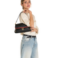 A woman wearing a cream blouse and light blue jeans carries a black shoulder bag with a red trim and gold hardware against a plain white background.