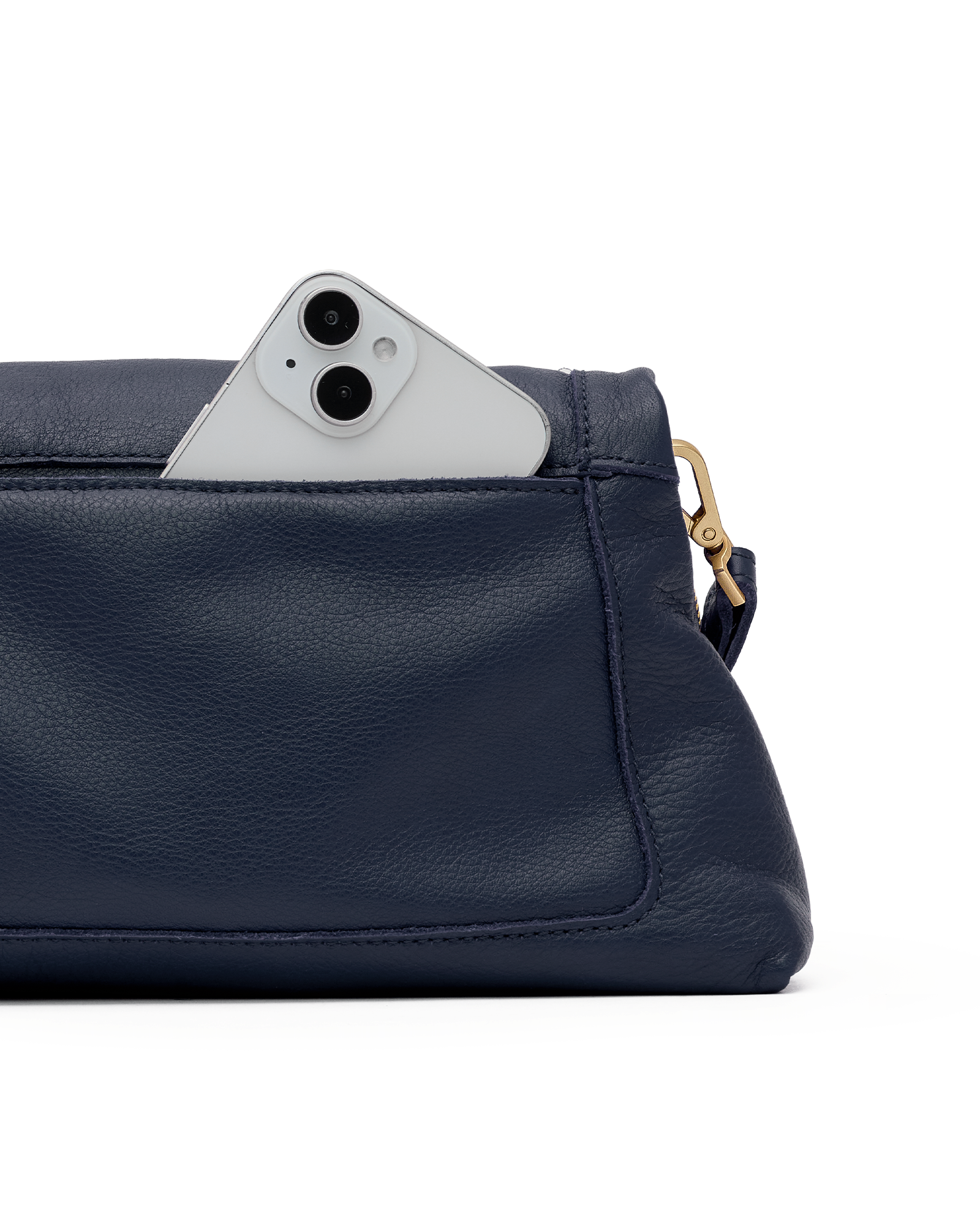 A close-up of a navy blue pebbled leather pouch or clutch with a white smartphone partially tucked into the top pocket, showing a gold-tone ring pull on a white background.
