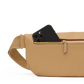 A tan pebbled leather crossbody bag with a gold zipper and a black smartphone partially tucked into the front pocket, shown against a clean white background.