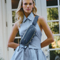 Model wearing a blue checkered dress with a blue waist bag outdoors.