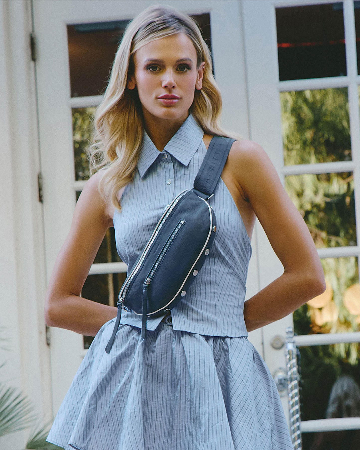 Model wearing a blue checkered dress with a blue waist bag outdoors.