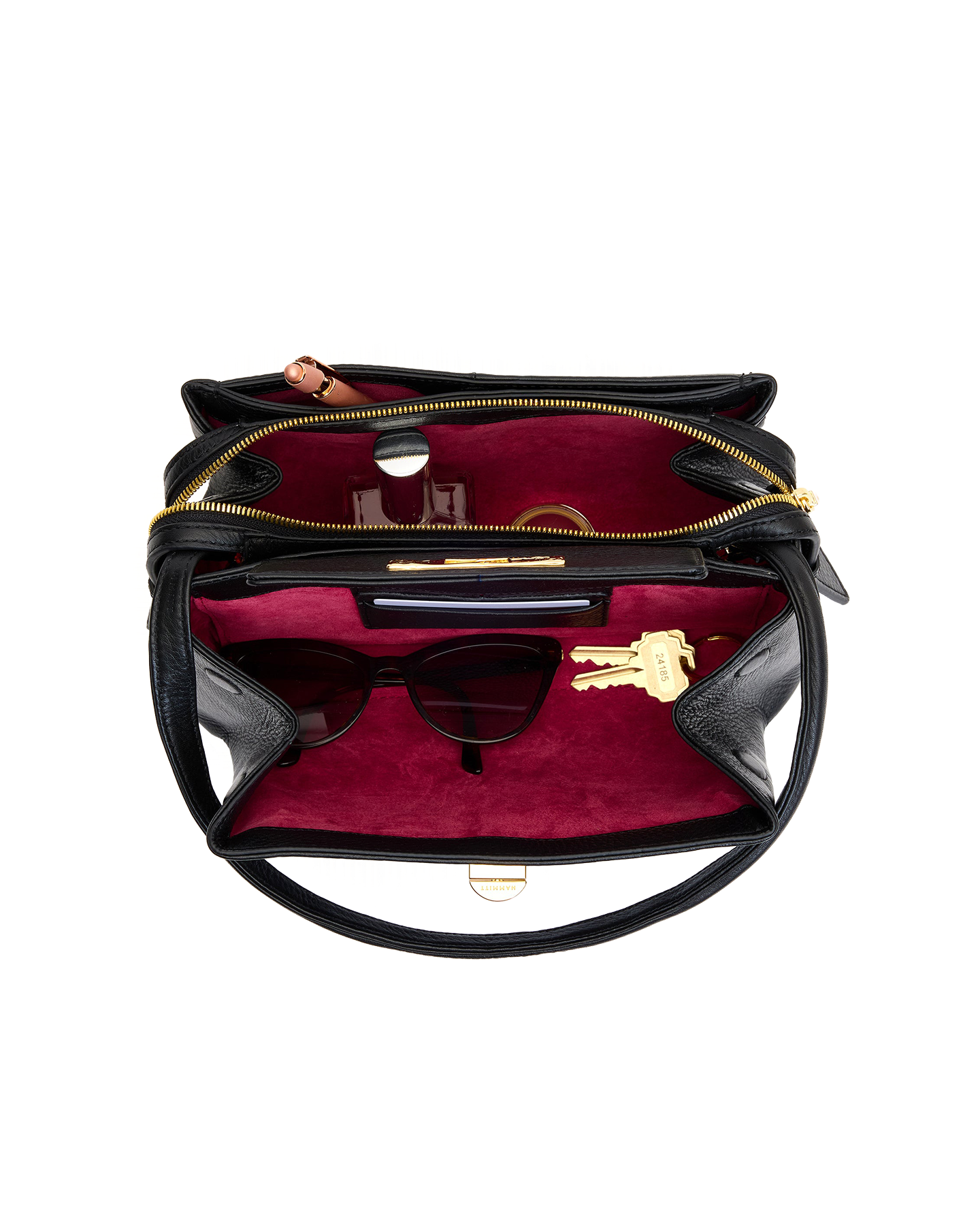 Black handbag with red interior containing sunglasses and a key on a white background