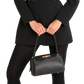 Person wearing a black coat and holding a matching black handbag on a white background