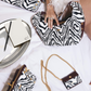 Zebra print handbags on a white surface with a clock and book.