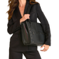 A woman in a black blazer and trousers carries a large black leather shoulder bag with silver-tone studs and a thin red accent stripe on the zipper, photographed against a clean white background.