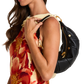 A woman wearing a cream and red floral dress carries a black crescent-shaped shoulder bag with gold hardware.