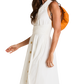 A woman wearing a sleeveless white midi dress with a gathered waist and gold-tone front buttons. She is carrying a bright orange shoulder bag.