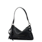 A black pebbled leather shoulder bag with a curved slouchy silhouette, featuring a single shoulder strap, a front zip pocket, and decorative silver-tone rivets and grommets on the side.
