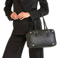 A black leather handbag with gold-tone hardware, carried by a model wearing a black blazer and trousers.