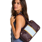 A model wearing a blue sleeveless top carries a structured leather handbag over her shoulder. The bag is deep burgundy with a wide light blue panel and a thin gold stripe detail.