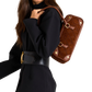 A woman in a black outfit carries a brown quilted leather shoulder bag with gold-tone hardware.