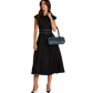 A woman modeling a black midi dress with a matching belt, holding a navy blue handbag.