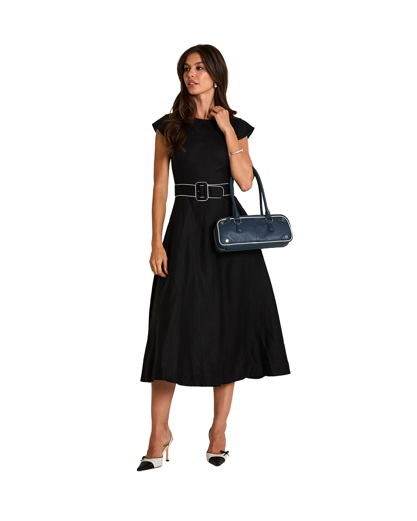A woman modeling a black midi dress with a matching belt, holding a navy blue handbag.