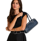 A woman in a black sleeveless top and skirt carries a navy blue leather handbag with white piping and silver hardware.
