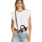 A woman modeling a white sleeveless top, light-wash blue jeans, a brown belt, and a clear crossbody bag with black hardware and strap.