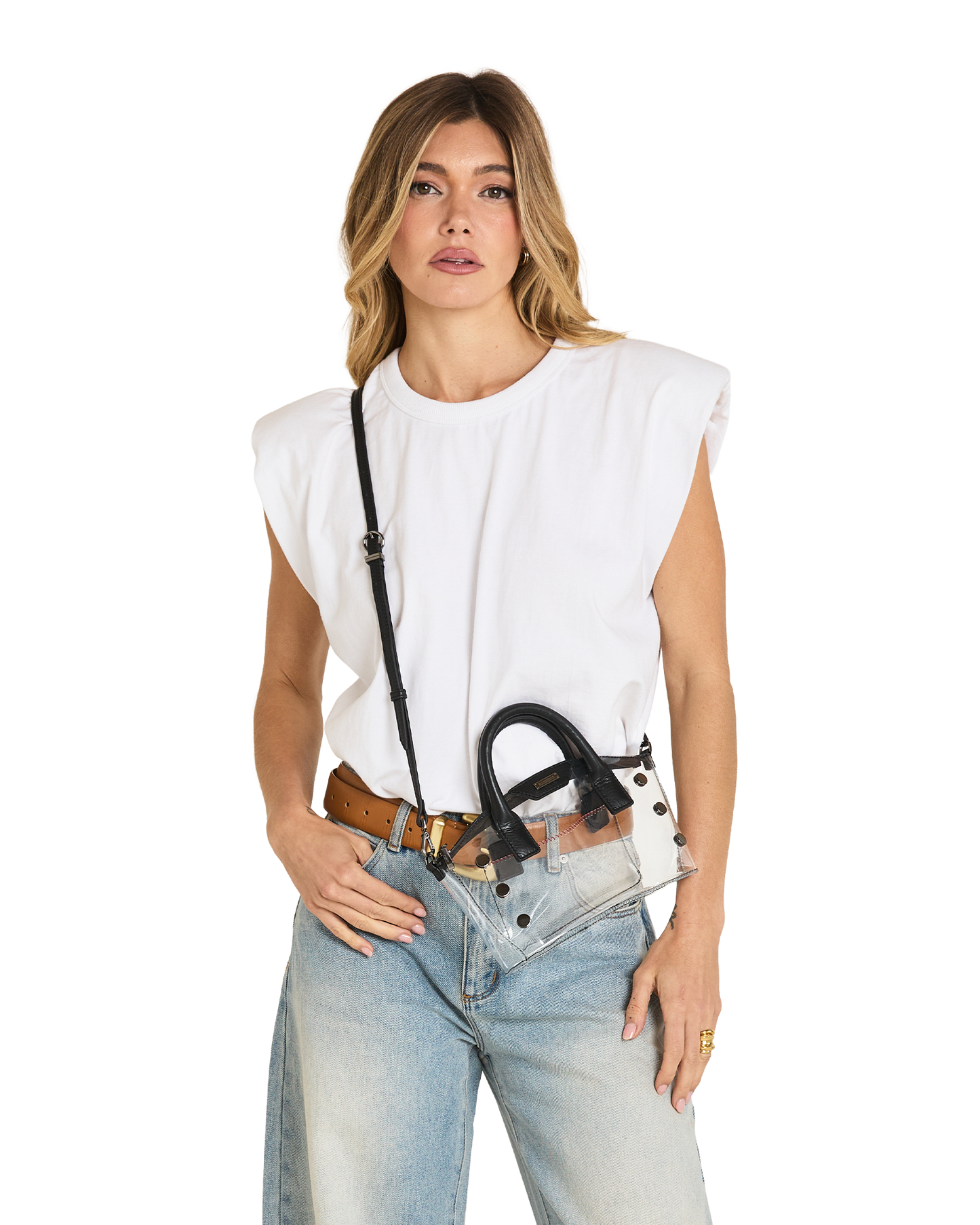 A woman modeling a white sleeveless top, light-wash blue jeans, a brown belt, and a clear crossbody bag with black hardware and strap.