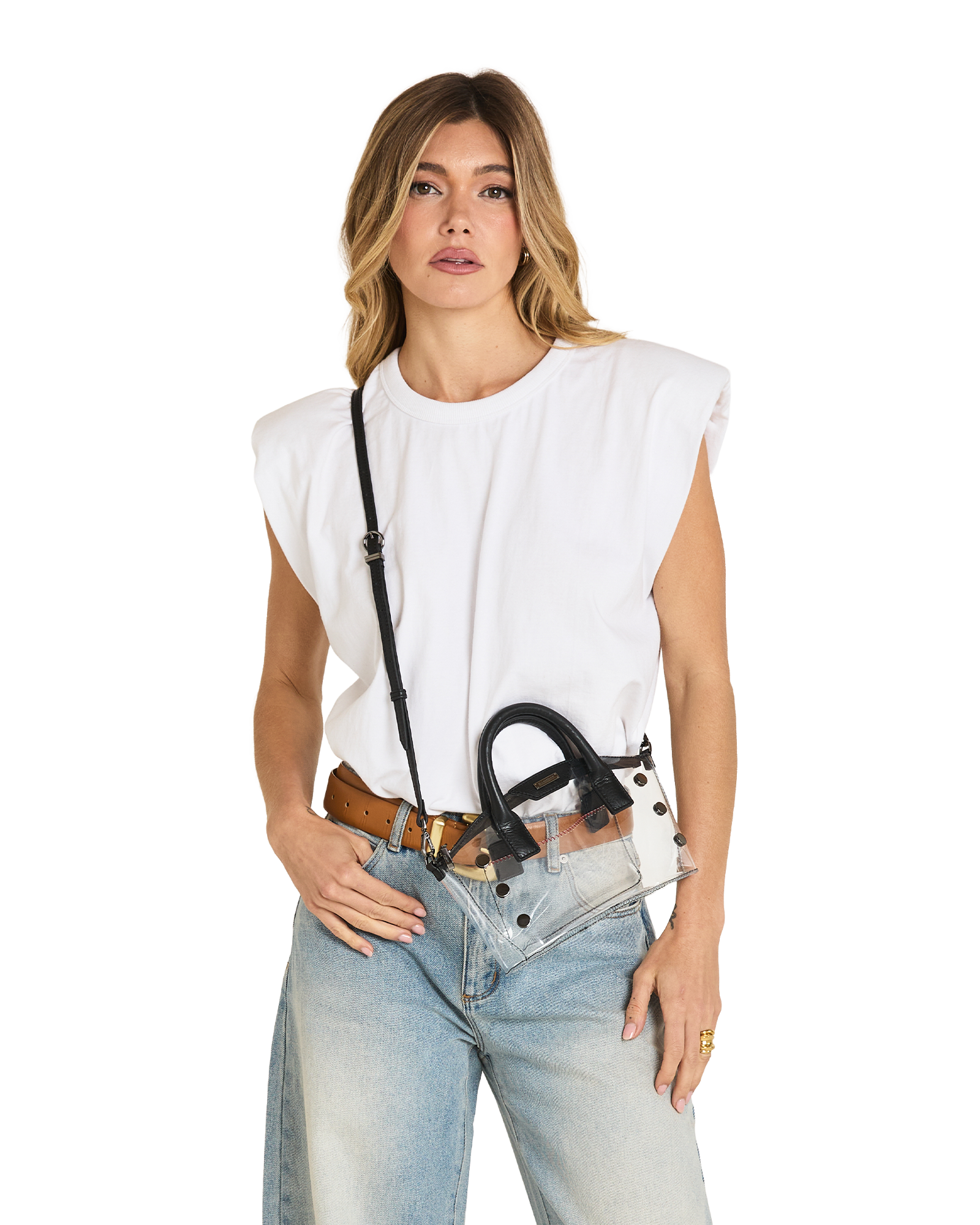 A woman modeling a white sleeveless top, light-wash blue jeans, a brown belt, and a clear crossbody bag with black hardware and strap.