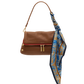 A brown leather shoulder bag with a red accent stripe along the front zipper, gold-tone hardware, and a blue, gold, and navy patterned silk scarf tied to the strap, shown on a plain white background.