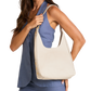 A woman wearing a blue sleeveless top and matching pants carries a large cream-colored leather hobo shoulder bag with gold-tone hardware.
