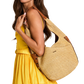 A woman in a yellow dress carries a large woven straw shoulder bag with brown leather trim and strap details against a plain white background.