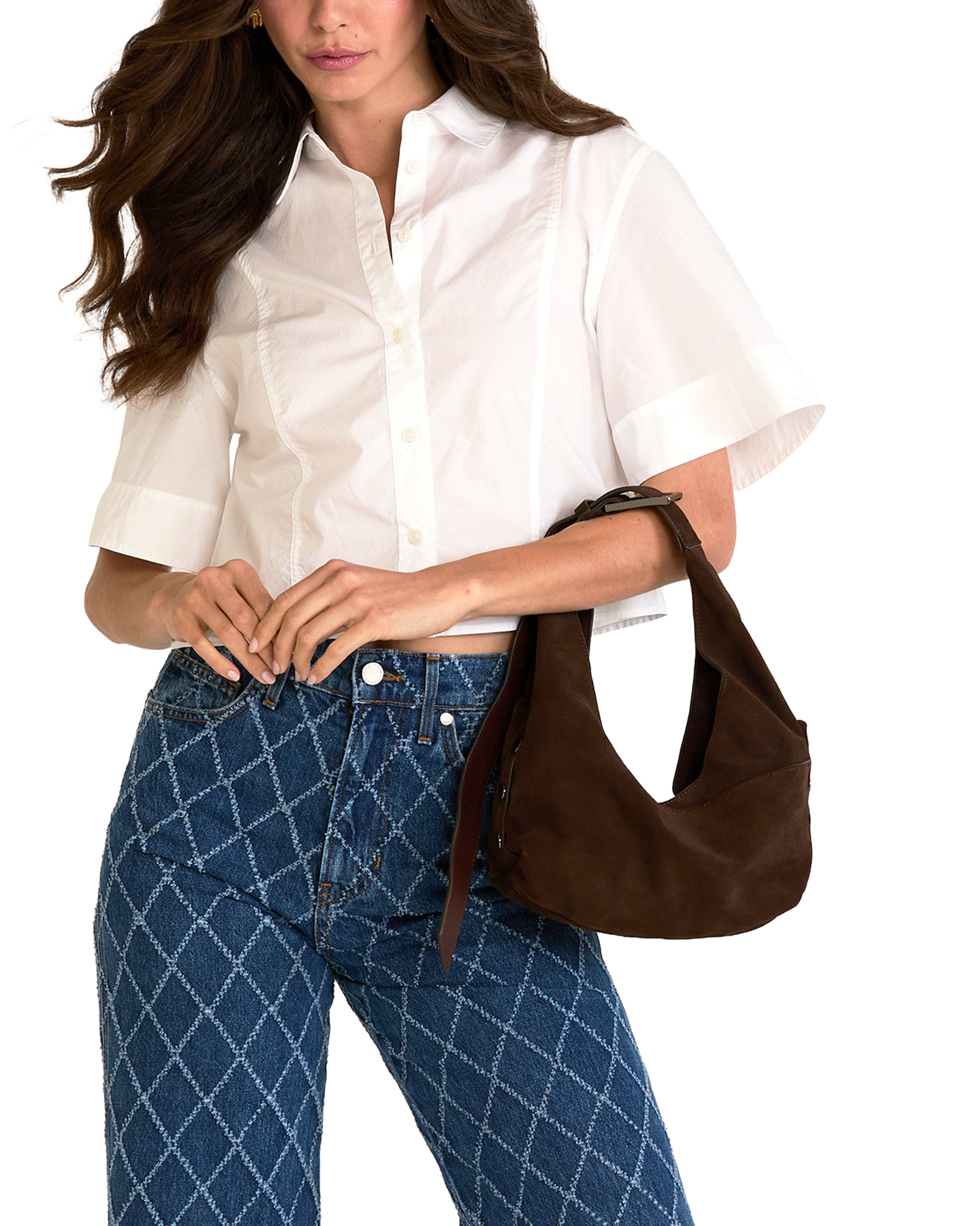 A woman wearing a white short-sleeve button-up shirt and blue patterned jeans, carrying a brown suede shoulder bag.