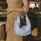 Model holding a light blue handbag in a bar setting.