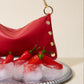 Red leather handbag with gold accents on a tray of ice and red peppers.
