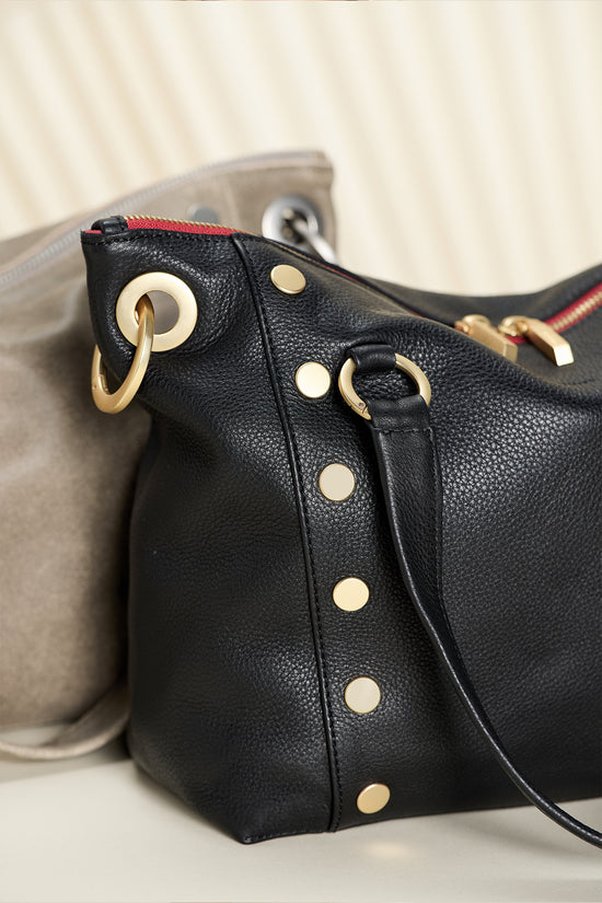 Detail image of rivitts on Daniel Med in black brushed gold red zip, with Daniel pewter med in brushed silver behind.