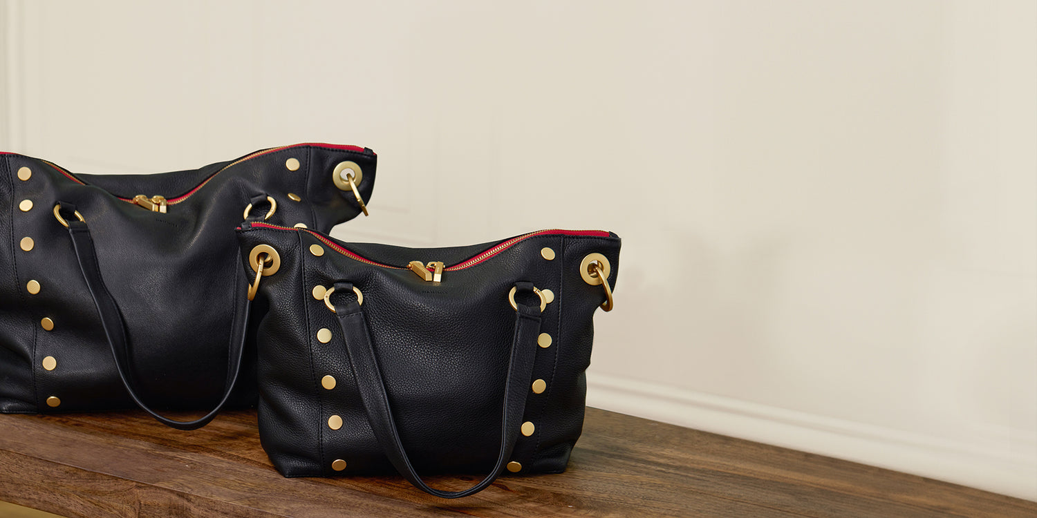 Two Daniels in Black Brushed Gold red Zip in both Lrg and Med on table.