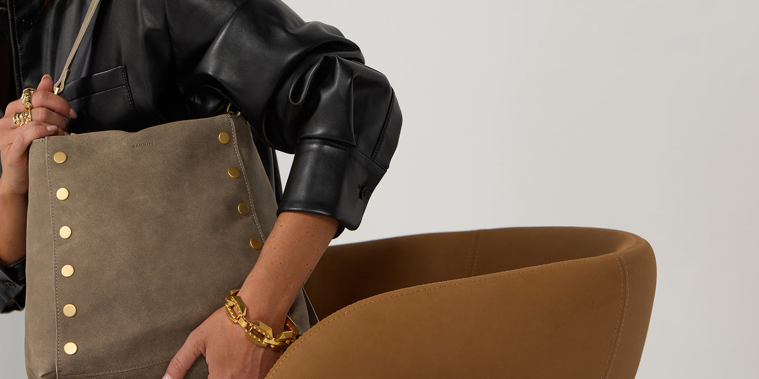 Model in black leather jacket holding Bryant LRg in Pewter bruhed gold over shoulder.