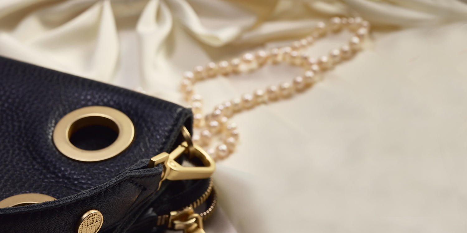 Image of the corner of Montana clutch sml in black brushed gold on white fabric and pearls 