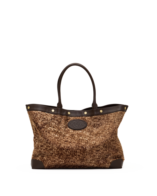 A structured tote bag with a brown and gold glittery woven body, dark brown leather trim, double top handles, and gold-tone hardware, shown against a plain white background.