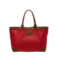 A red leather tote bag with brown leather trim, double shoulder straps, brass-tone hardware, and a circular embossed logo patch on the front, shown against a plain white background.