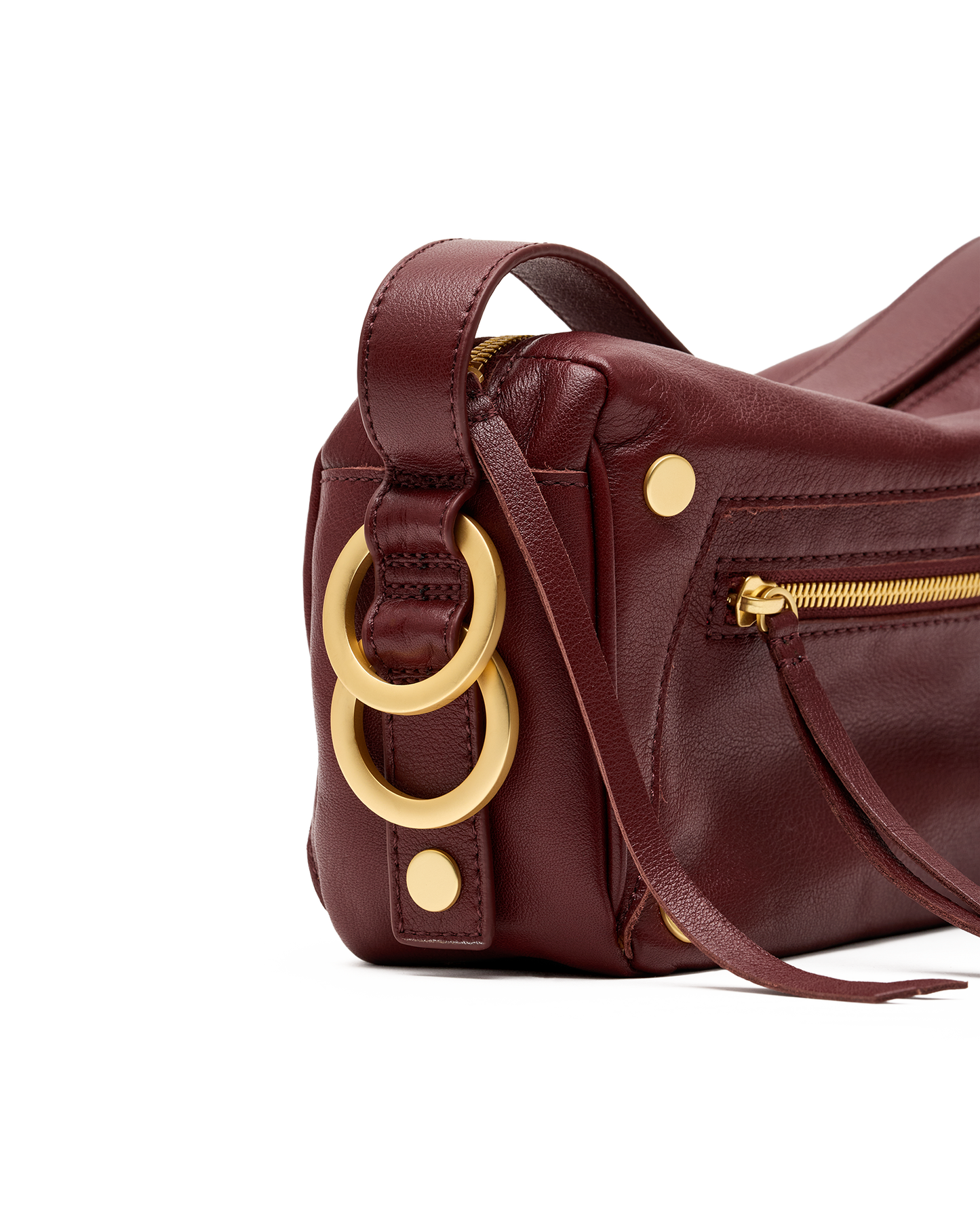 A close-up of a dark burgundy leather handbag featuring large gold-tone double rings and gold hardware on a white background.