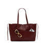 A burgundy leather tote bag with dual shoulder straps and a front slip pocket containing tortoiseshell sunglasses and a smartphone, shown on a plain white background.