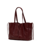 A dark burgundy leather tote bag with double shoulder straps, drawstring ties, and gold-tone metal studs along the bottom edge, shown against a plain white background.