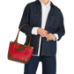 A model wearing a dark blue denim shirt jacket, white button-down shirt, and dark blue jeans, holding a red leather tote bag with brown leather handles and trim.