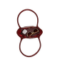 A small glossy burgundy handbag with a top handle, shown from above on a plain white background. Inside the bag, a pair of gold-framed sunglasses and a white rectangular item are partially visible.