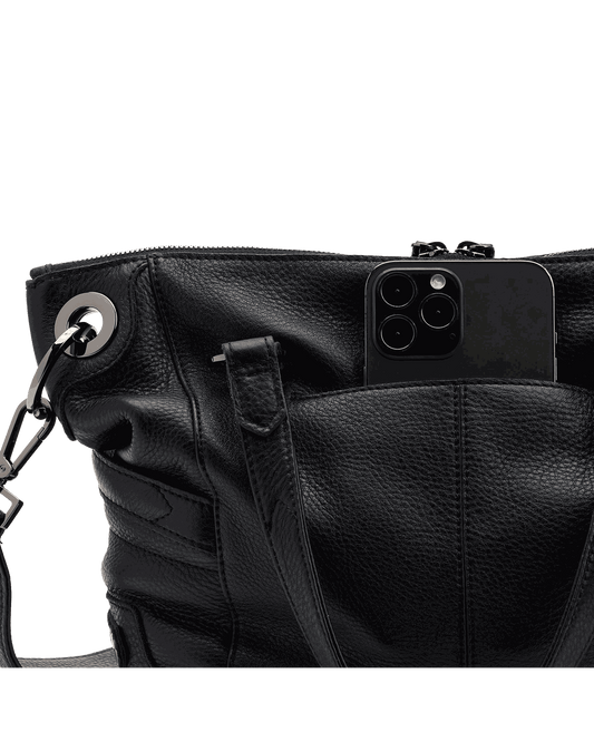 Black leather handbag with a phone inside on a black background